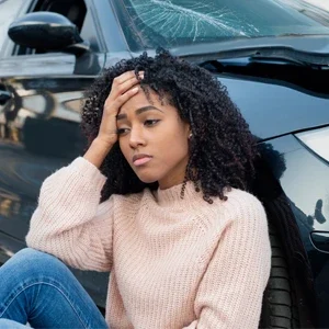 A woman sitting on the ground with head pain after an auto accident
